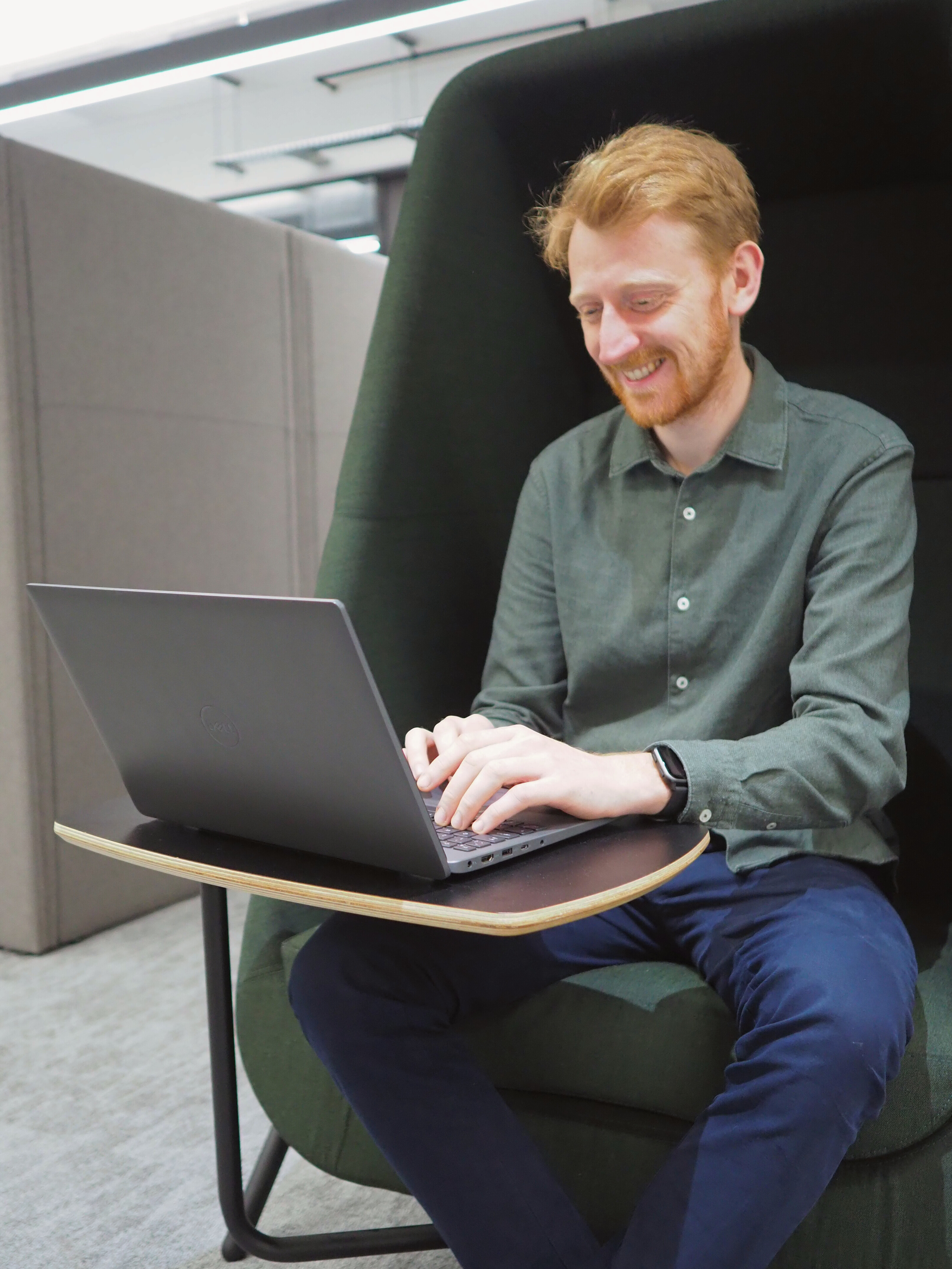 Individual working on a laptop whilst smiling