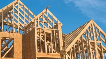 Wooden framing of a house under construction against a blue sky.