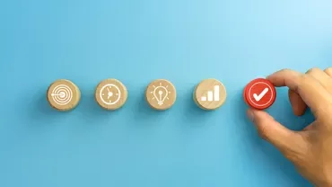 Hand picking a red checkmark disc among other icons on blue background.