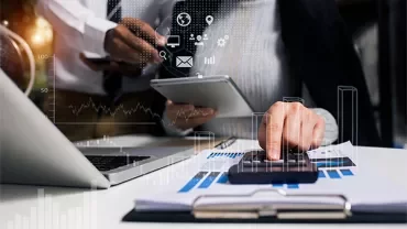 Business professionals reviewing data on tablet and calculator with graphs overlayed.