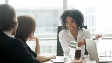Person presenting ideas in a meeting, smiling and engaging with colleagues.