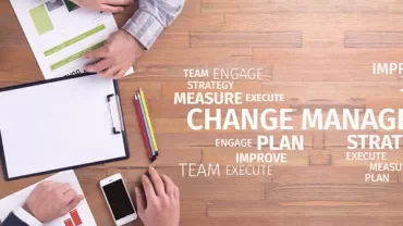 Two people working on change management documents at a wooden table.