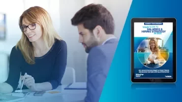 Two people discussing work at a table, with a digital hiring guide displayed on a tablet.