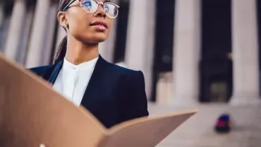 Person holding a folder in front of a large building.