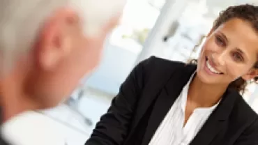 Professional interaction in a modern office setting, two people engaged in conversation.