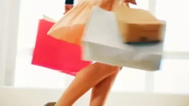 Person walking with colorful shopping bags in hand.