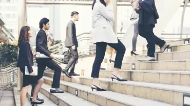 People in business attire walking up outdoor steps.