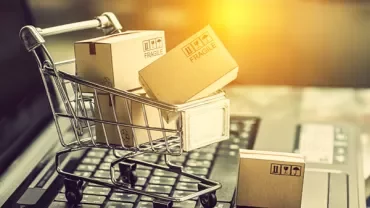 Mini shopping cart with cardboard boxes on a laptop.