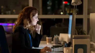 Person working at a computer late at night in an office.