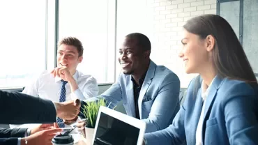 Group of colleagues in a meeting, smiling and discussing.