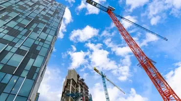 Skyscrapers under construction with cranes against a blue sky